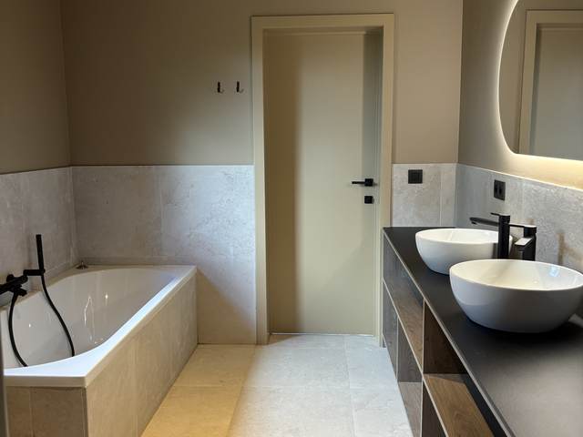 Badkamer met bad en twee wastafels